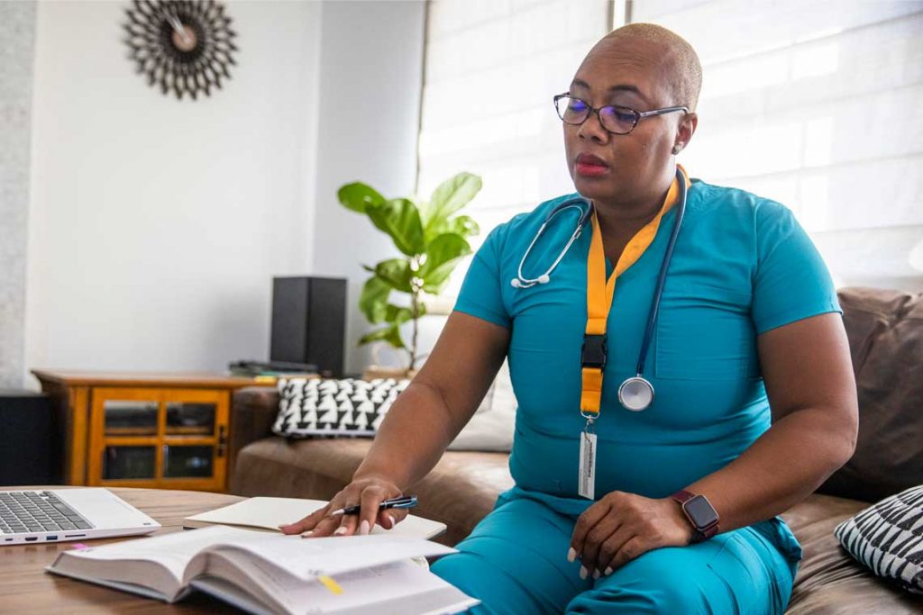nurse studying with textbook and laptop