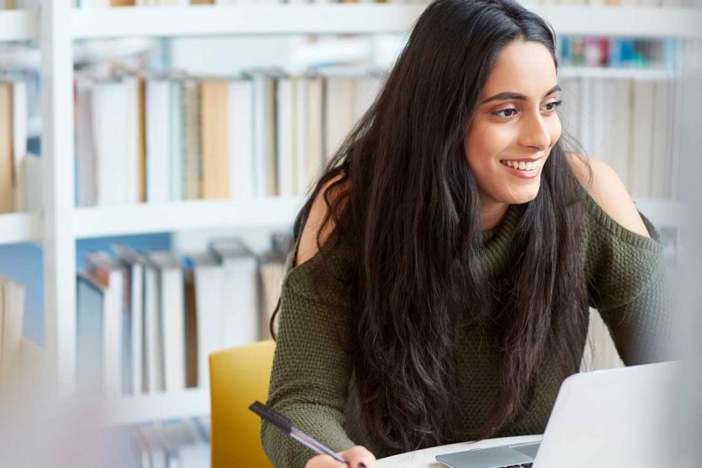 woman on laptop takes notes