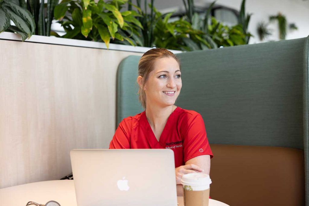 NEU nursing student smiling at desk