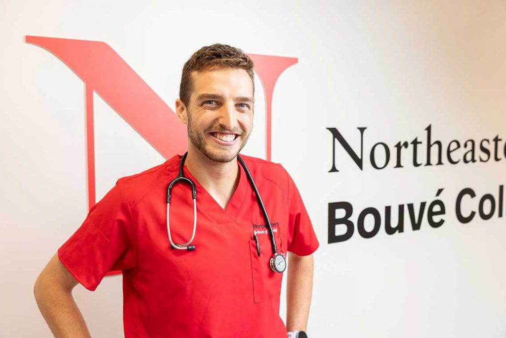NEU nursing student standing by wall smiling