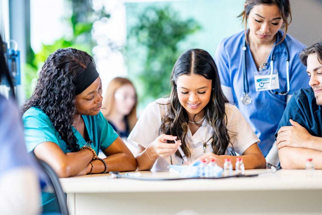 nursing students practicing skills at table