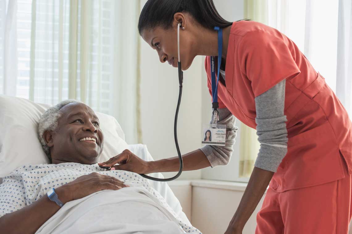 Nursing student using stethoscope on bed patient